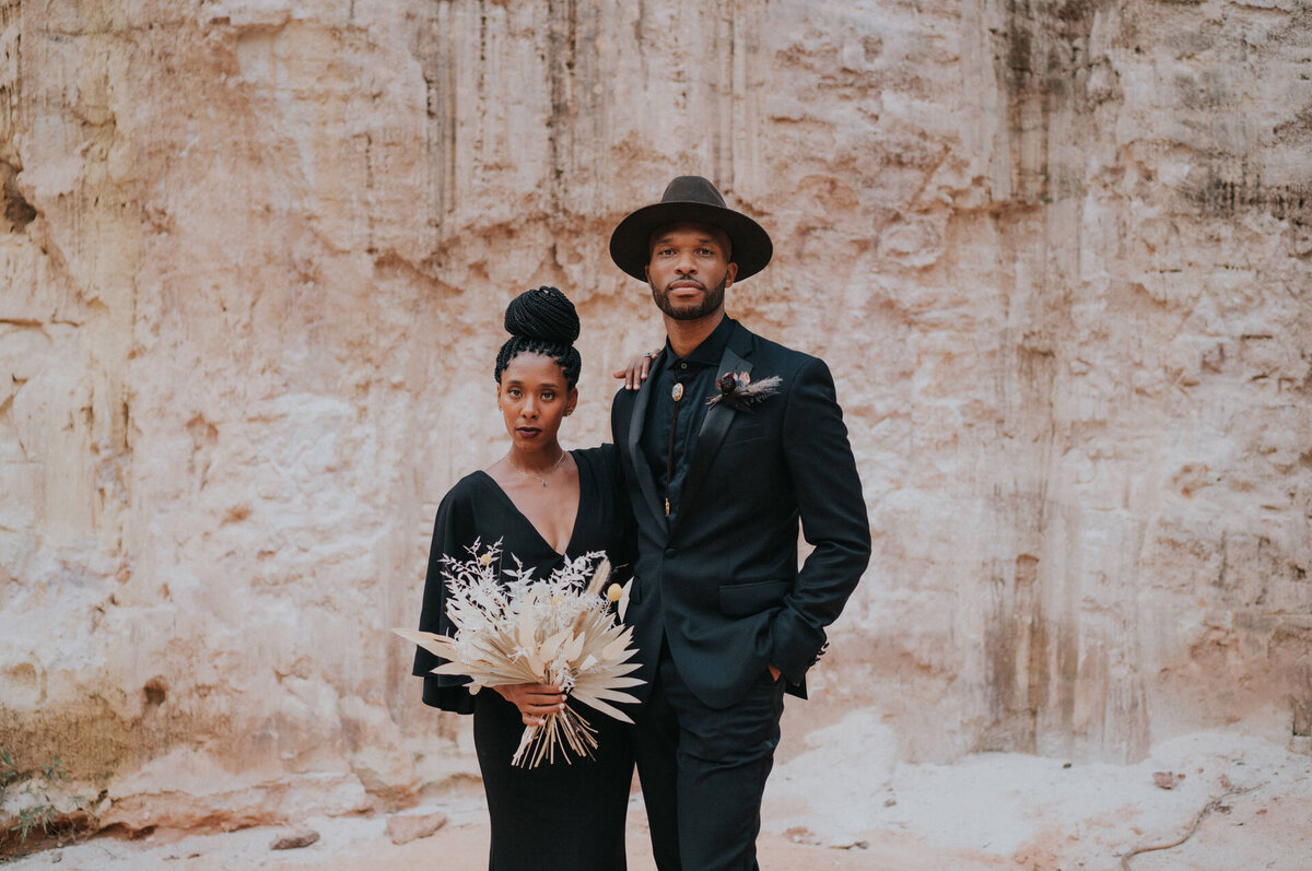 Black bride and groom wearing black outfits standing in the desert