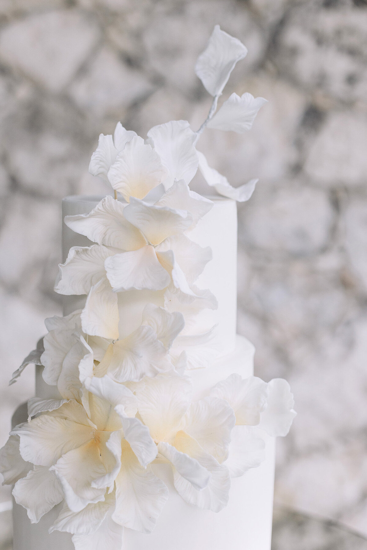 All-white tiered wedding cake with delicate floral accents for White Whisper luxury wedding in Tuscany
