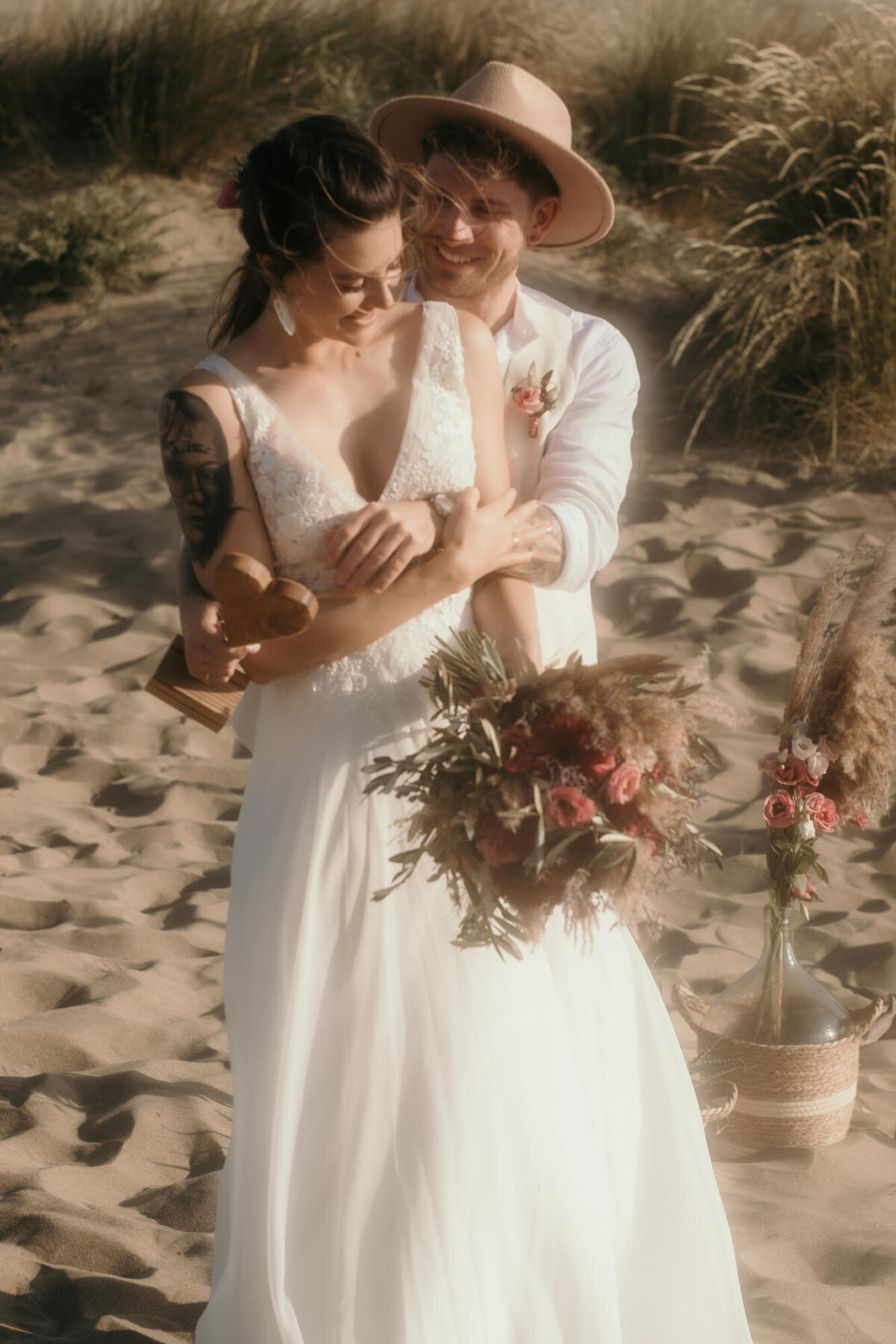 Nach der Trauung umarmt der Bräutigam seine Braut glücklich von hinten. Sie blickt zu Boden.