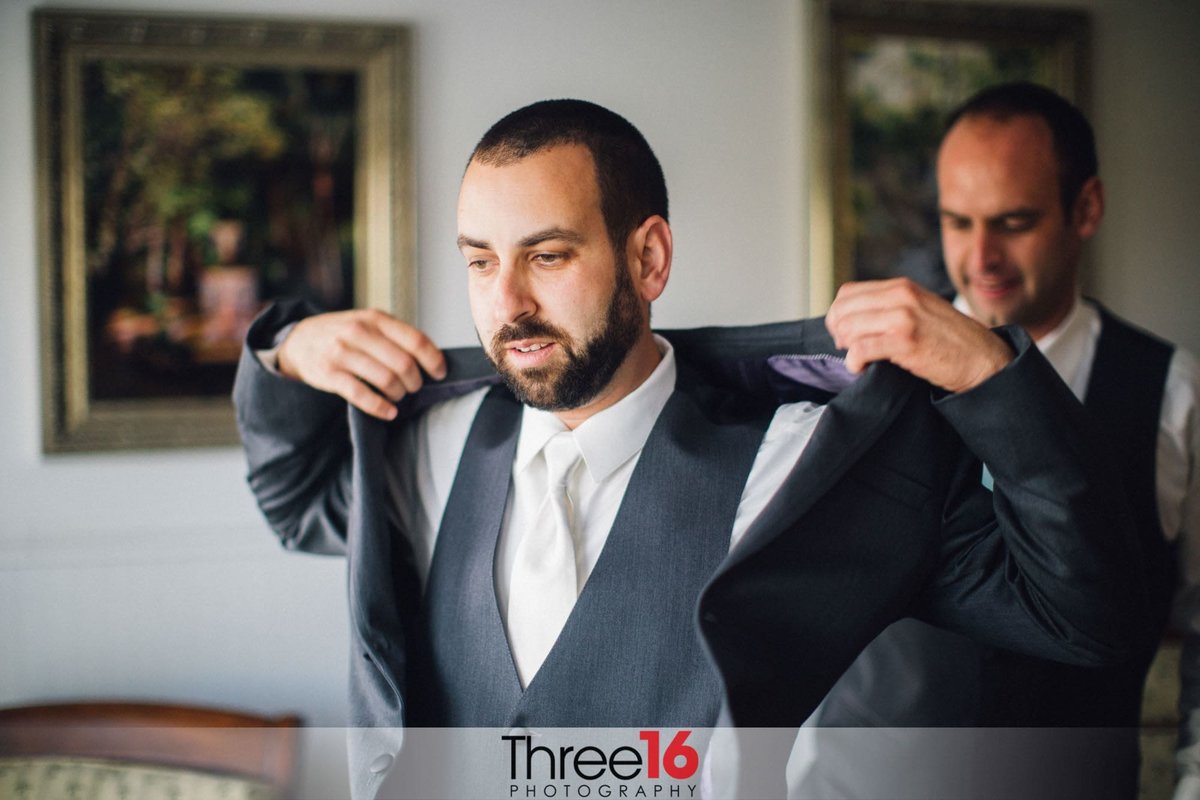 Groom putting on his suit jacket
