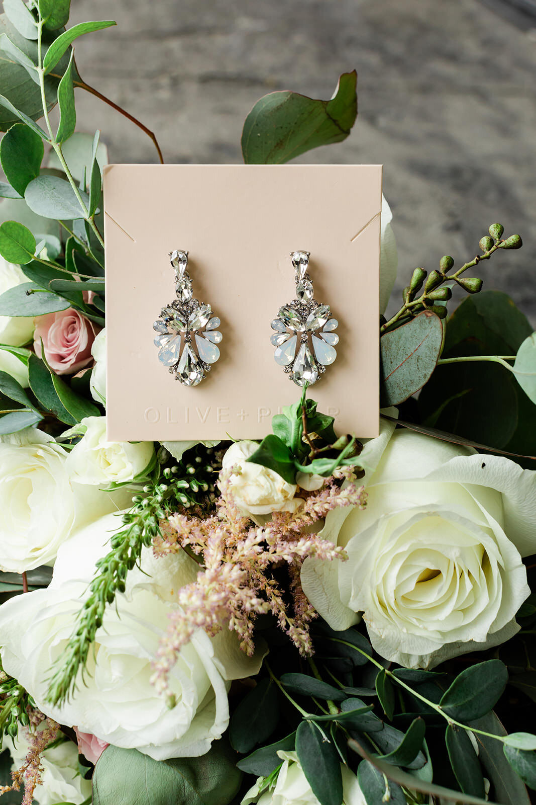 Bride earrings laying on bridal bouquet