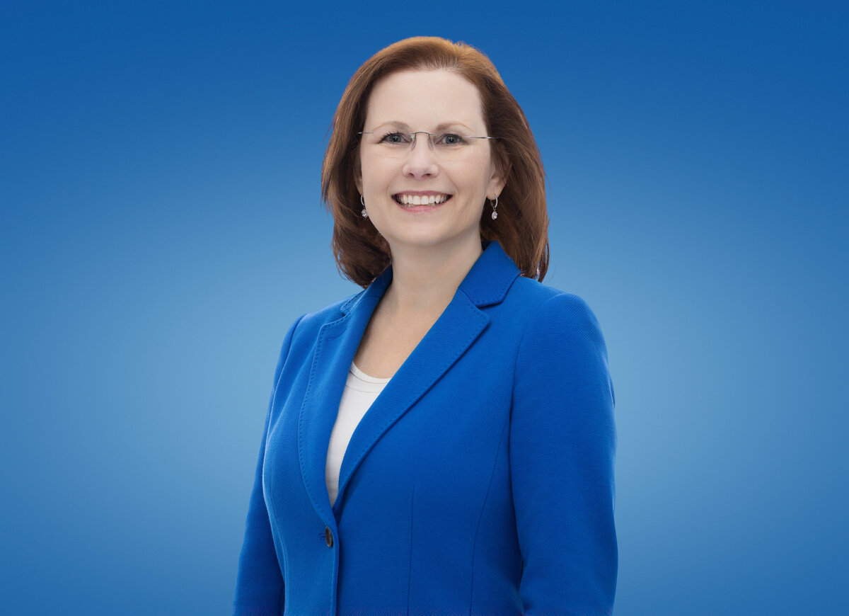 An elegant studio portrait of Gloria Johnston, captured in Cincinnati, presenting her in a striking royal blue blazer that commands attention. This image showcases Gloria with a warm, inviting smile, complemented by her neatly styled auburn hair and classic eyeglasses, which together project both professionalism and approachability. The portrait’s clear, focused quality makes it an excellent choice for personal branding and professional headshots in the Cincinnati area. Her Caucasian ethnicity and poised demeanor are prominently featured, reflecting a strong personal brand.