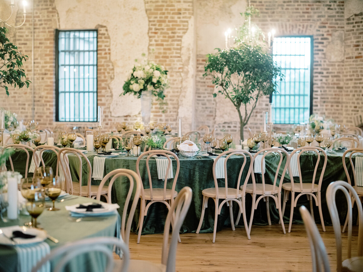 A stunning arrangement of an elegant green tablescape featuring floral decor, gold accents, and candlelight, perfect for creating a memorable reception experience at Twenty-One Magazine.