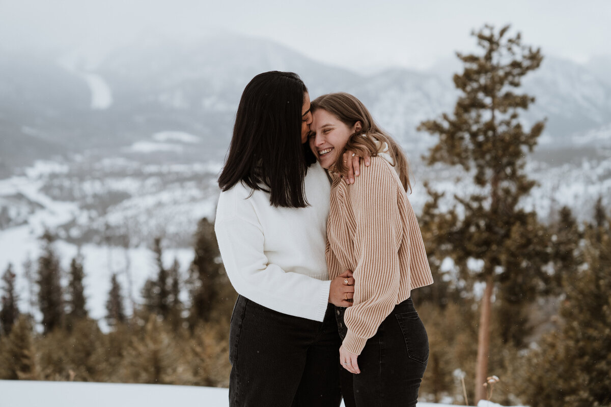 Romantic mountain moment with couple embracing at snowy Sapphire Point overlook in Breckenridge.