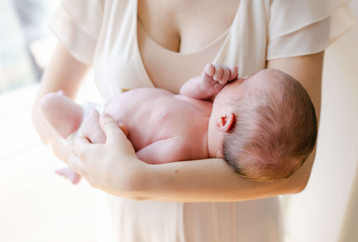 In-home newborn photography Bay Area, mom holding baby in natural light.