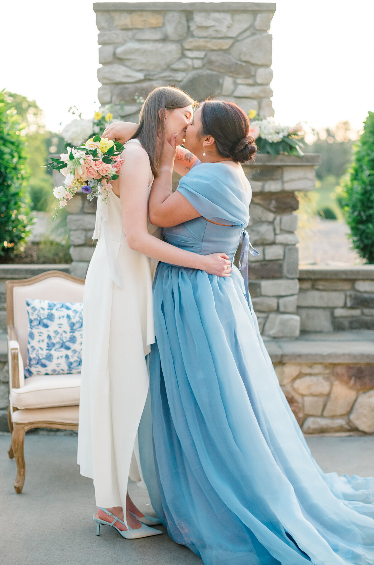 Two brides kissing in front of the fireplace at the Granary at Valley Pike in Weyers Cave, Virginia. Captured by Charlottesville Wedding Photographer Bethany Aubre Photography.