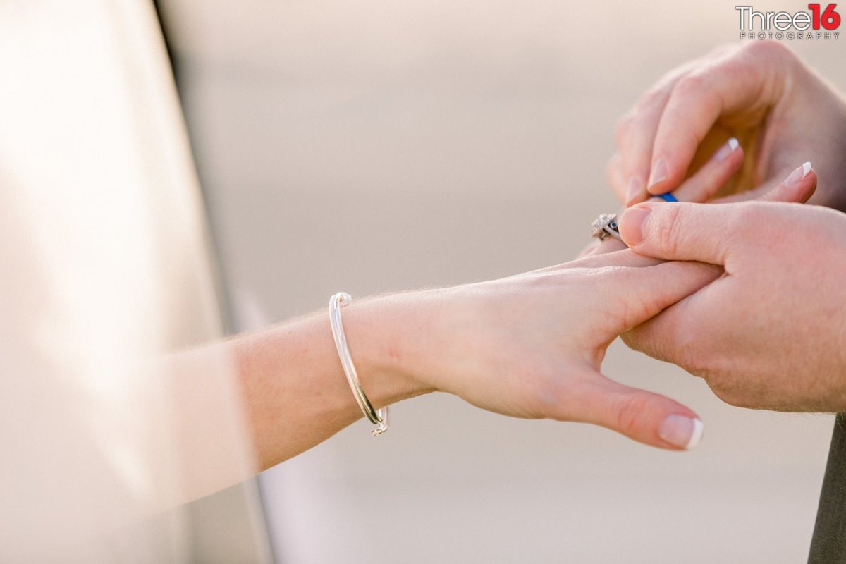 Groom places ring on his brides finger