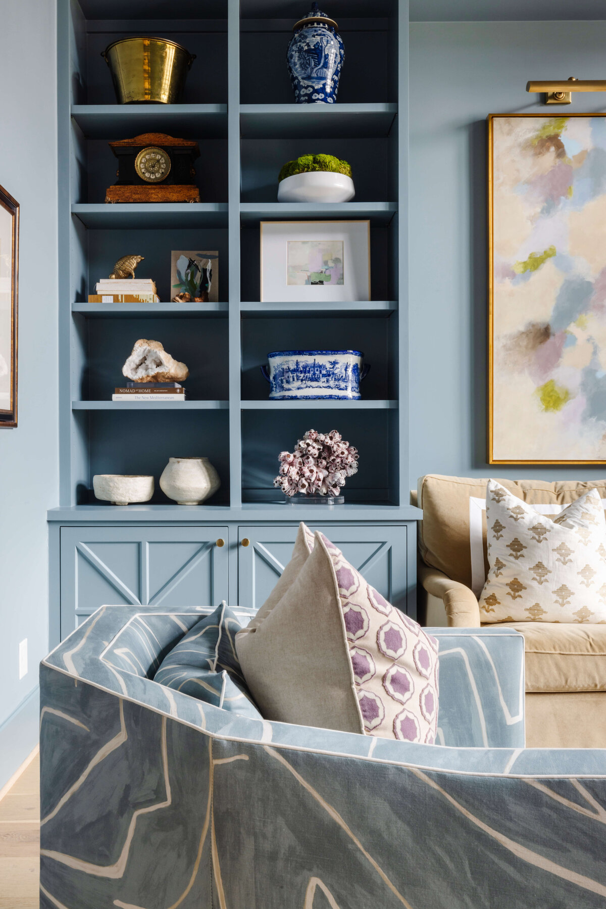 oyster creek studios missouri city new build blue shelves and cabinets in living room with blue armchair and abstract artwork