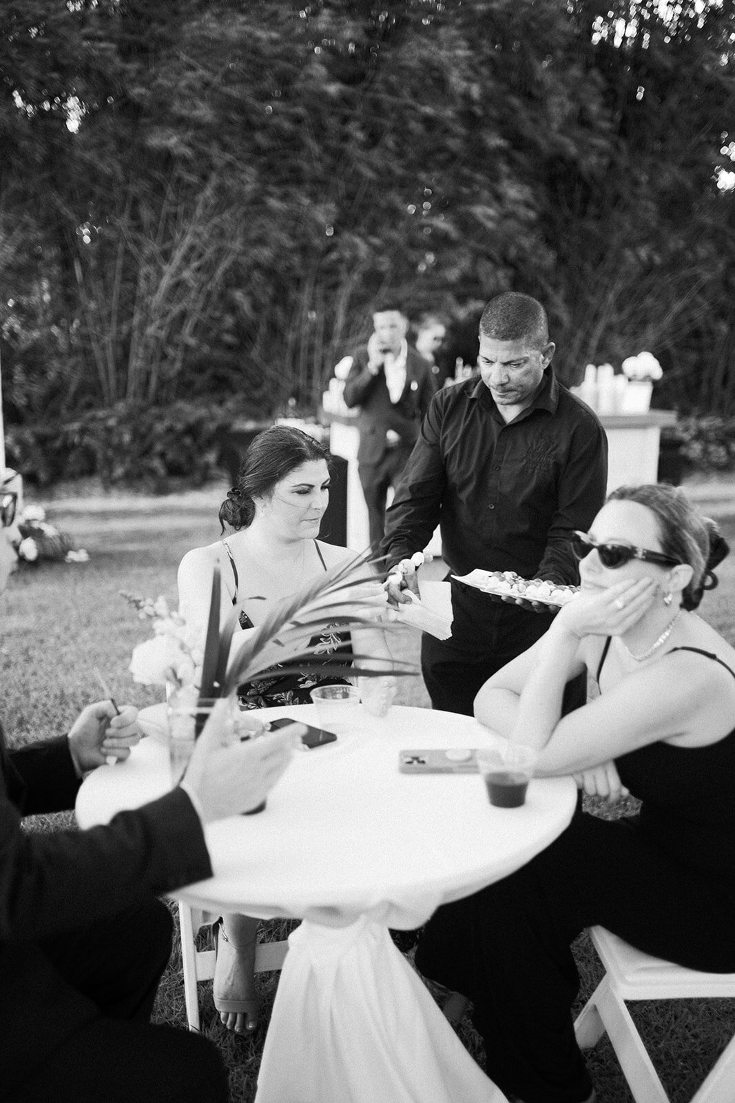 A timeless black-and-white image capturing wedding guests being served appetizers as they enjoy a sophisticated cocktail hour at Stephanie and Bradley’s Islamorada wedding. Photographed by Claudia Amalia Photography.