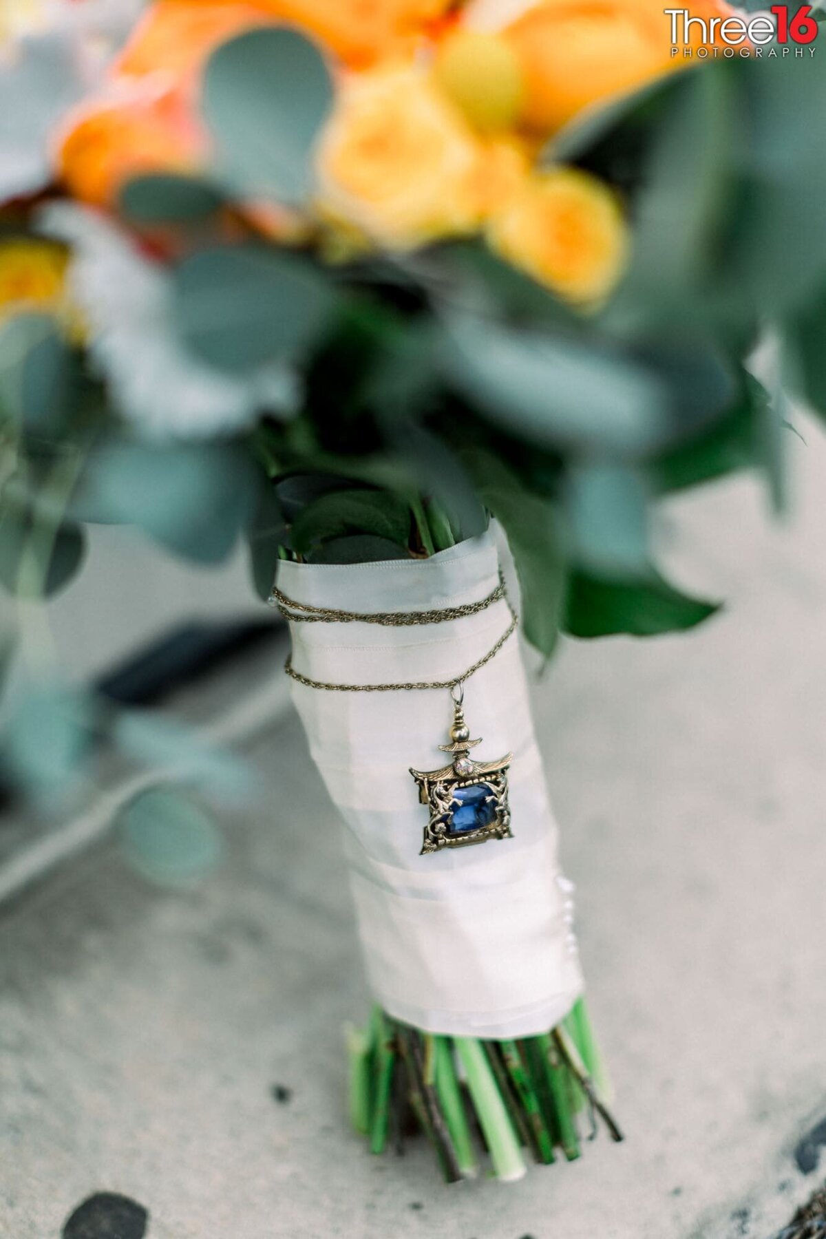 Necklace that is borrowed and blue is wrapped around the Bride's bouquet