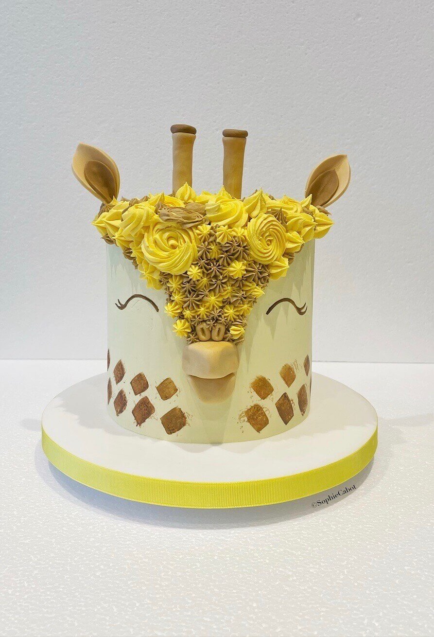 A cake with a giraffe theme, where the top of the cake is a giraffe design