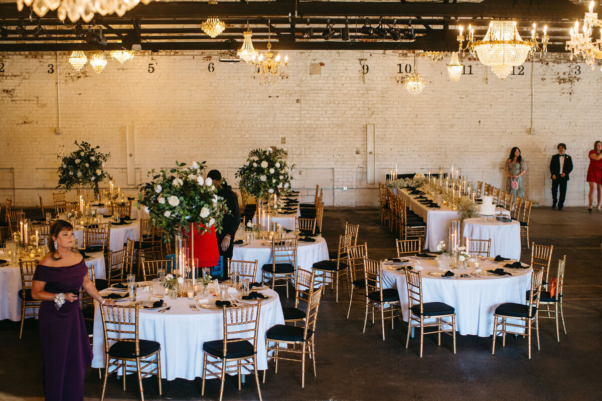 An intimate outdoor wedding ceremony under hanging lanterns with dappled sunlight filtering through the trees.