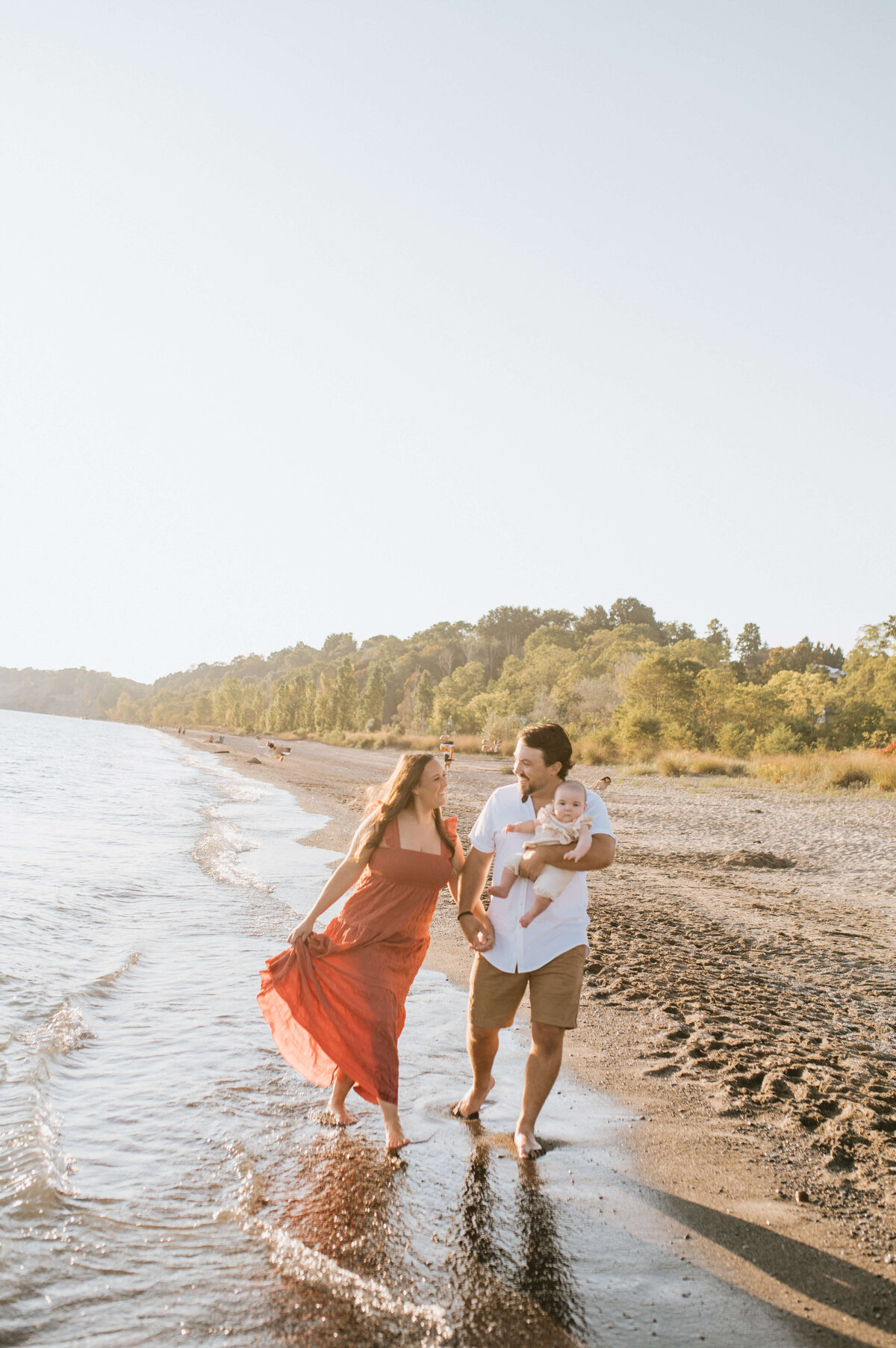 Woman-walking-in-water-with-husband-and-baby