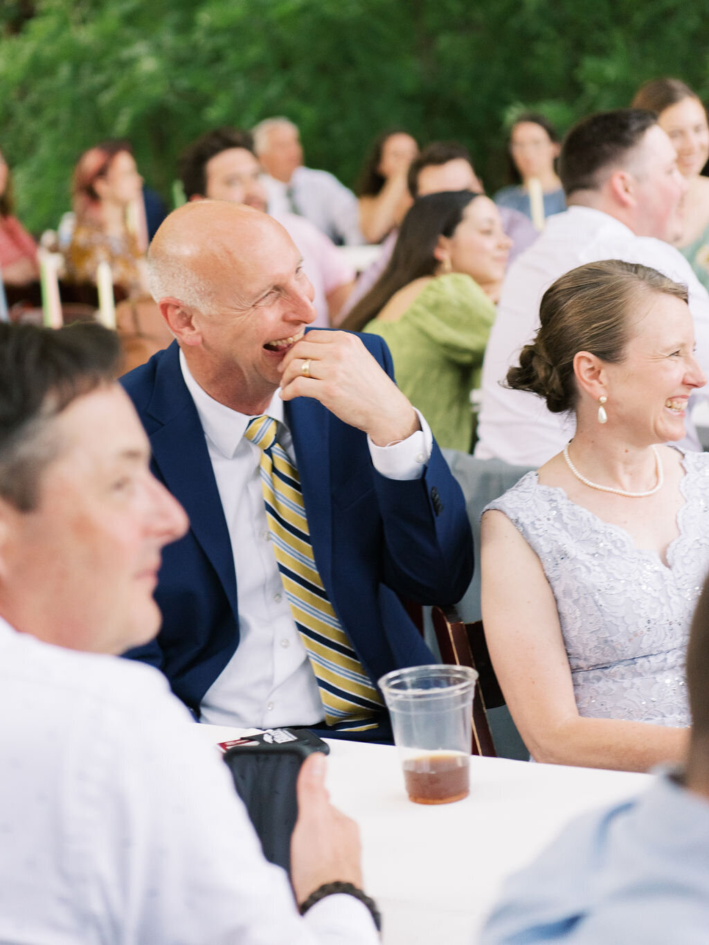 Parents of the groom laugh during toasts at a wedding reception