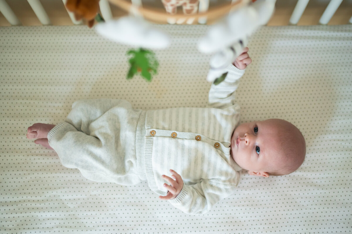 Baby laying in crib looking up at mobile