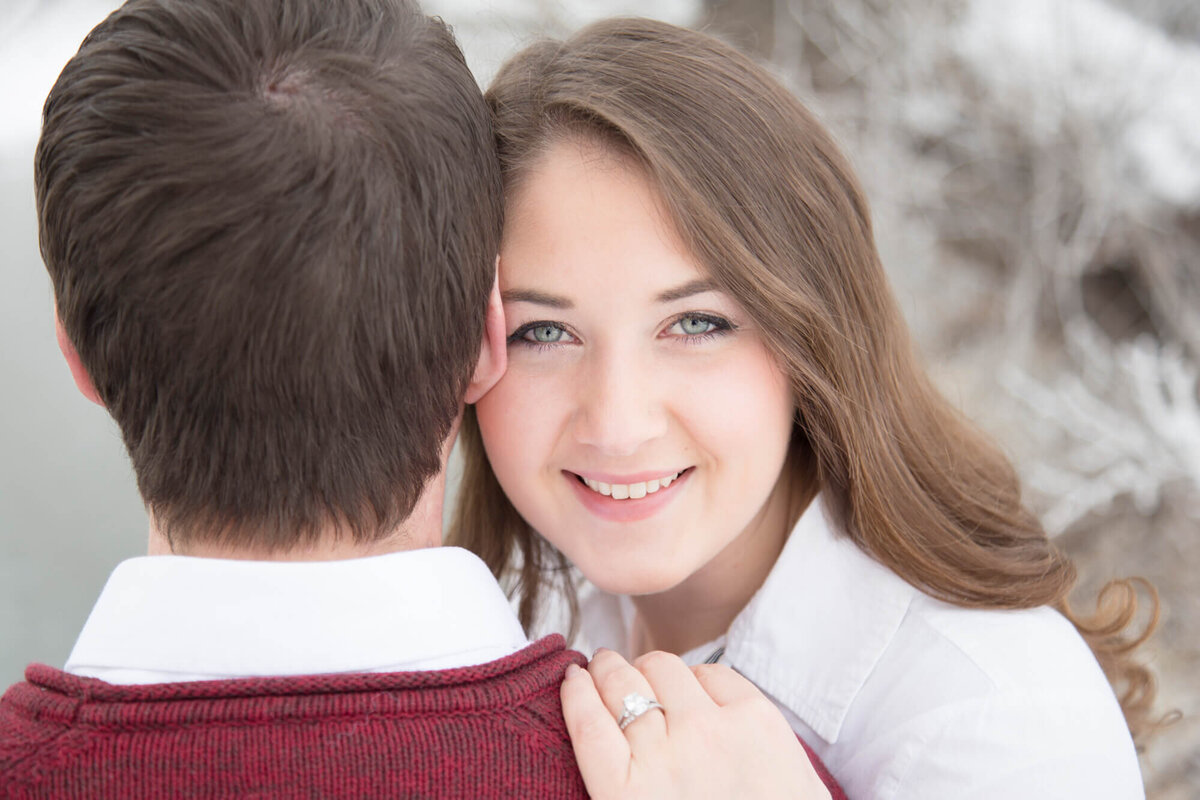 a woman looking over fiance's shoulder during their frosty engagement session