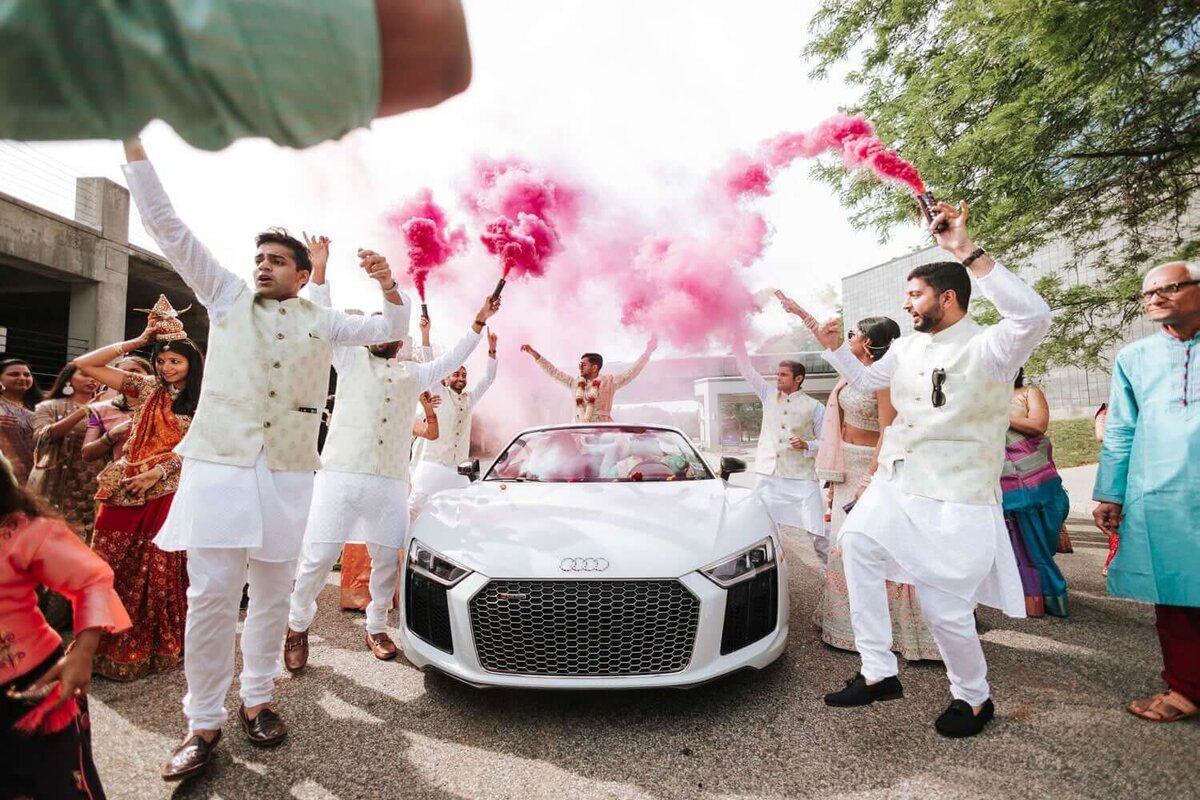 Bride and groom in the car with pink smoke celebrated by friends and family in New Jersey.