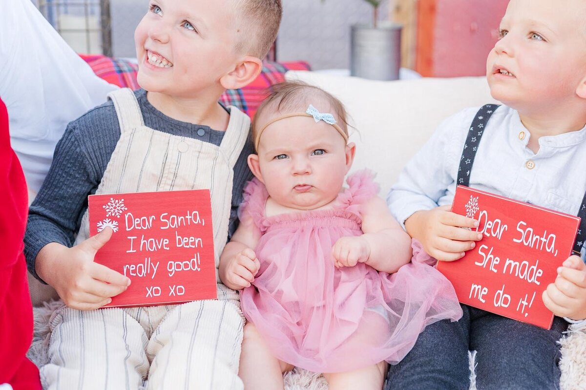 2 siblings holding Santa sign with baby girl during red truck minis in Fairfax, VA
