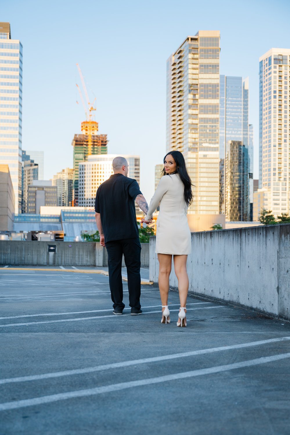 man and woman walk on rooftop for engagement photo