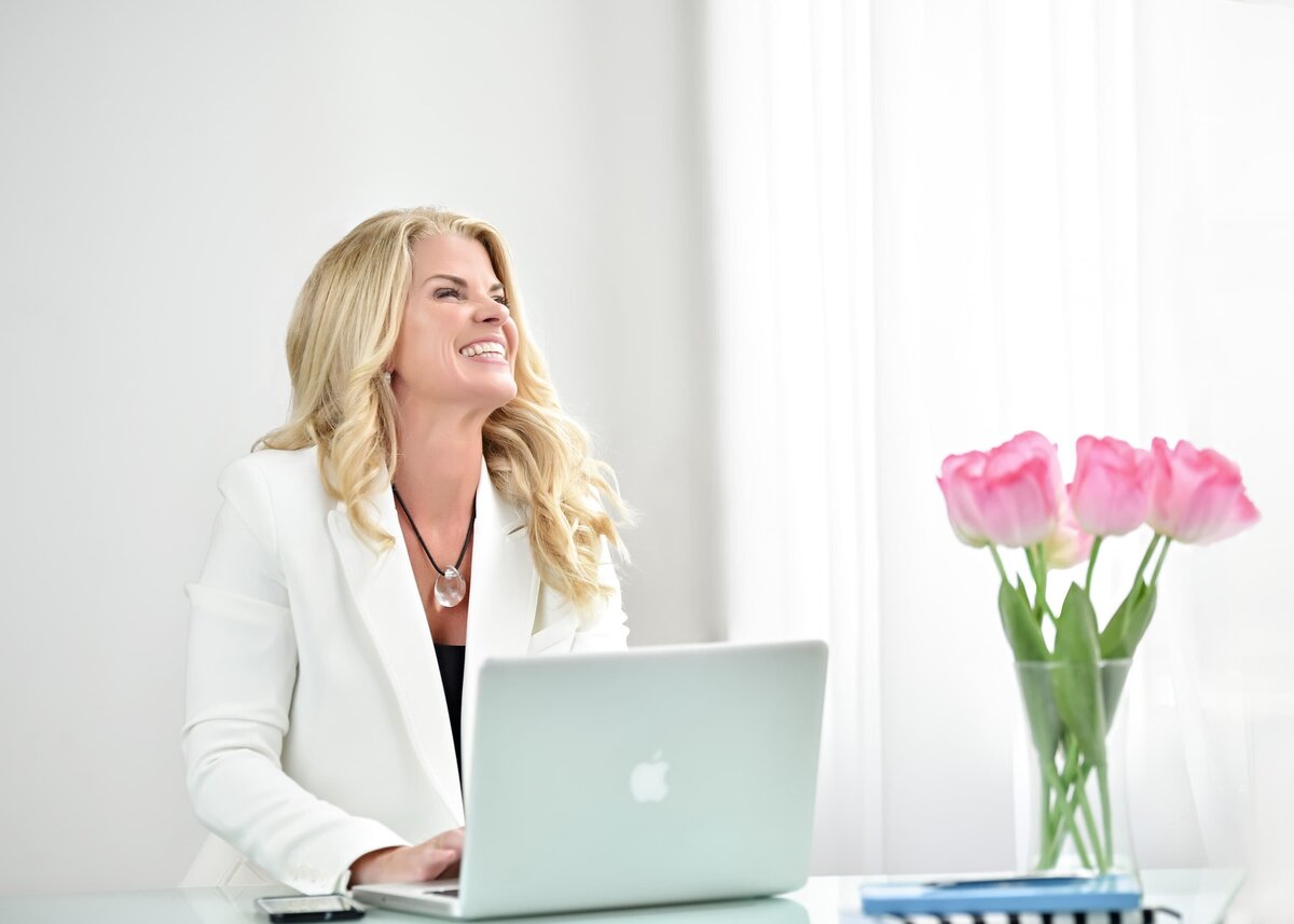 Professional branding photos Milton featuring a confident business owner working at a modern desk with fresh flowers.