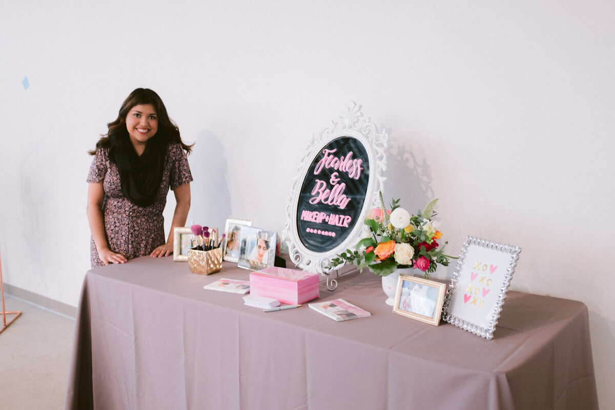 Wedding table that has wedding details on top, and a lady standing beside it