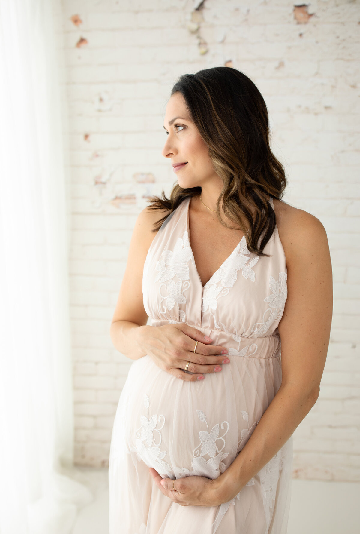 pregnant mother in cream maternity gown holding baby bump for maternity photoshoot