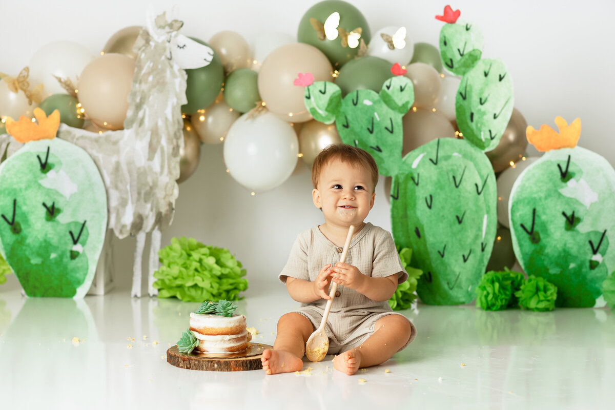 One year old Tampa baby enjoying a personalized luxury cake smash session with cactus themed decorations