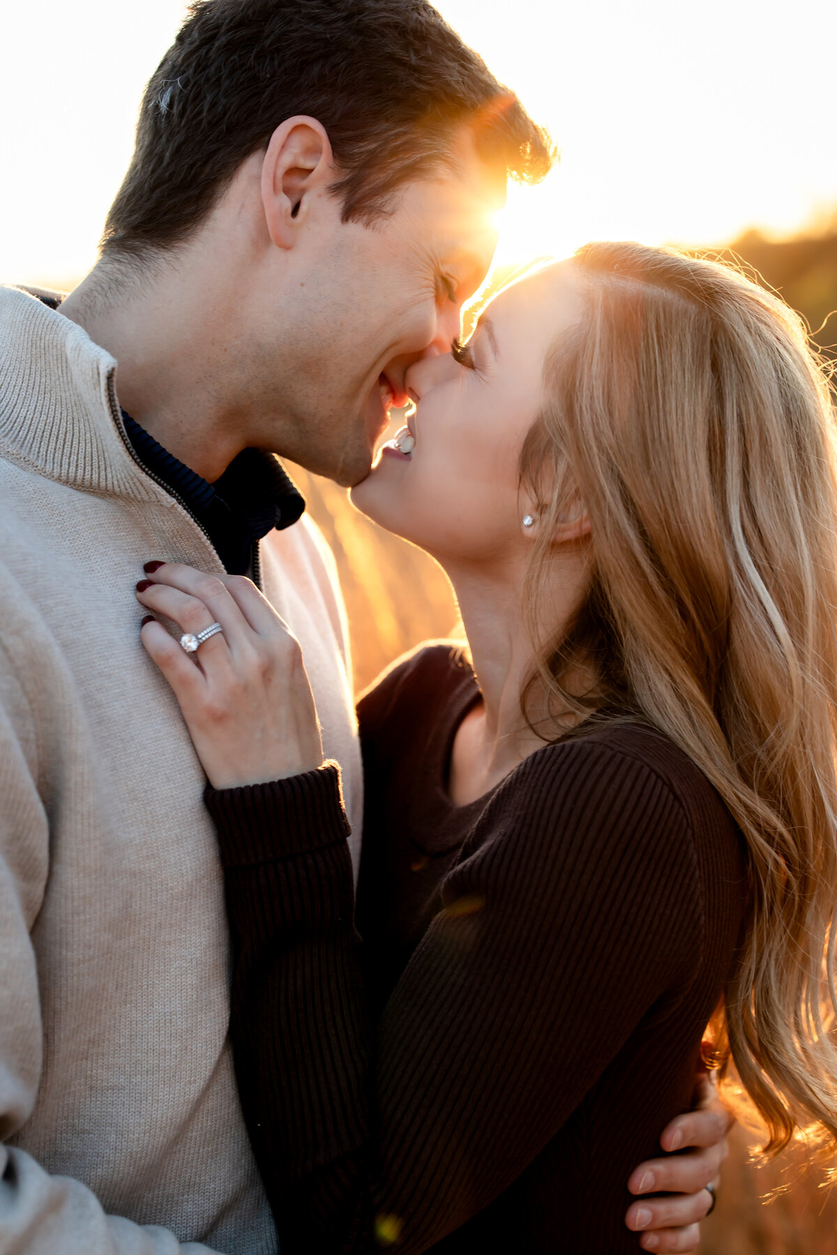 a couple embrace eachother with a kiss as the sunlight peaks between them