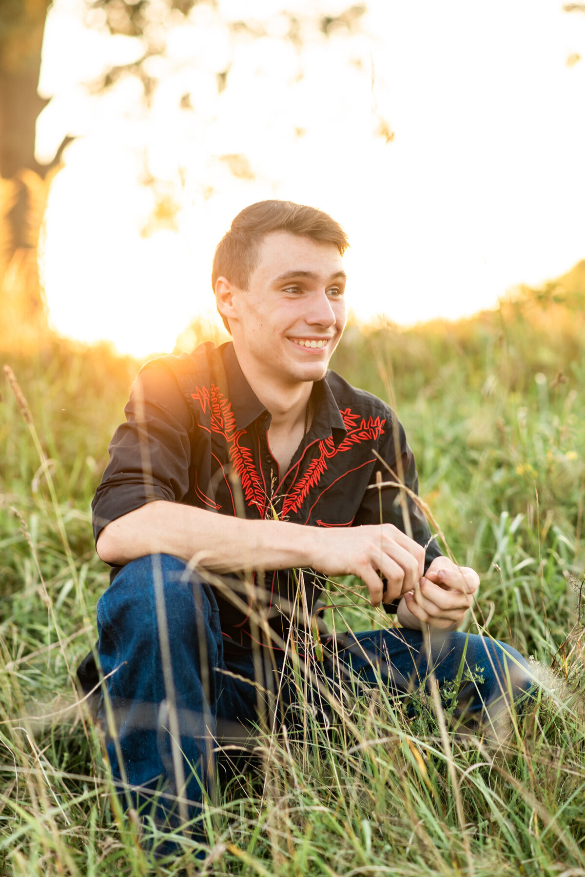 Senior boy laughing off camera in field at sunset