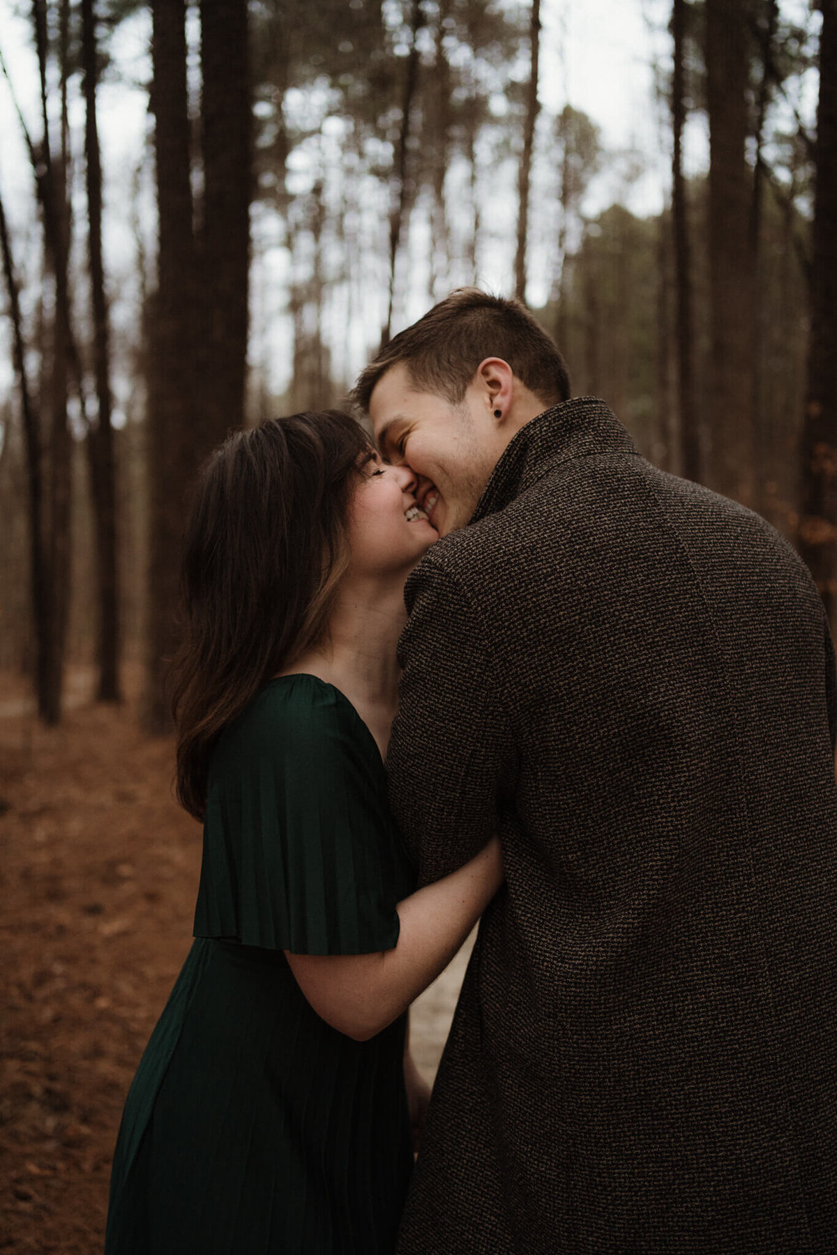 couple laughing and almost kissing in the woods