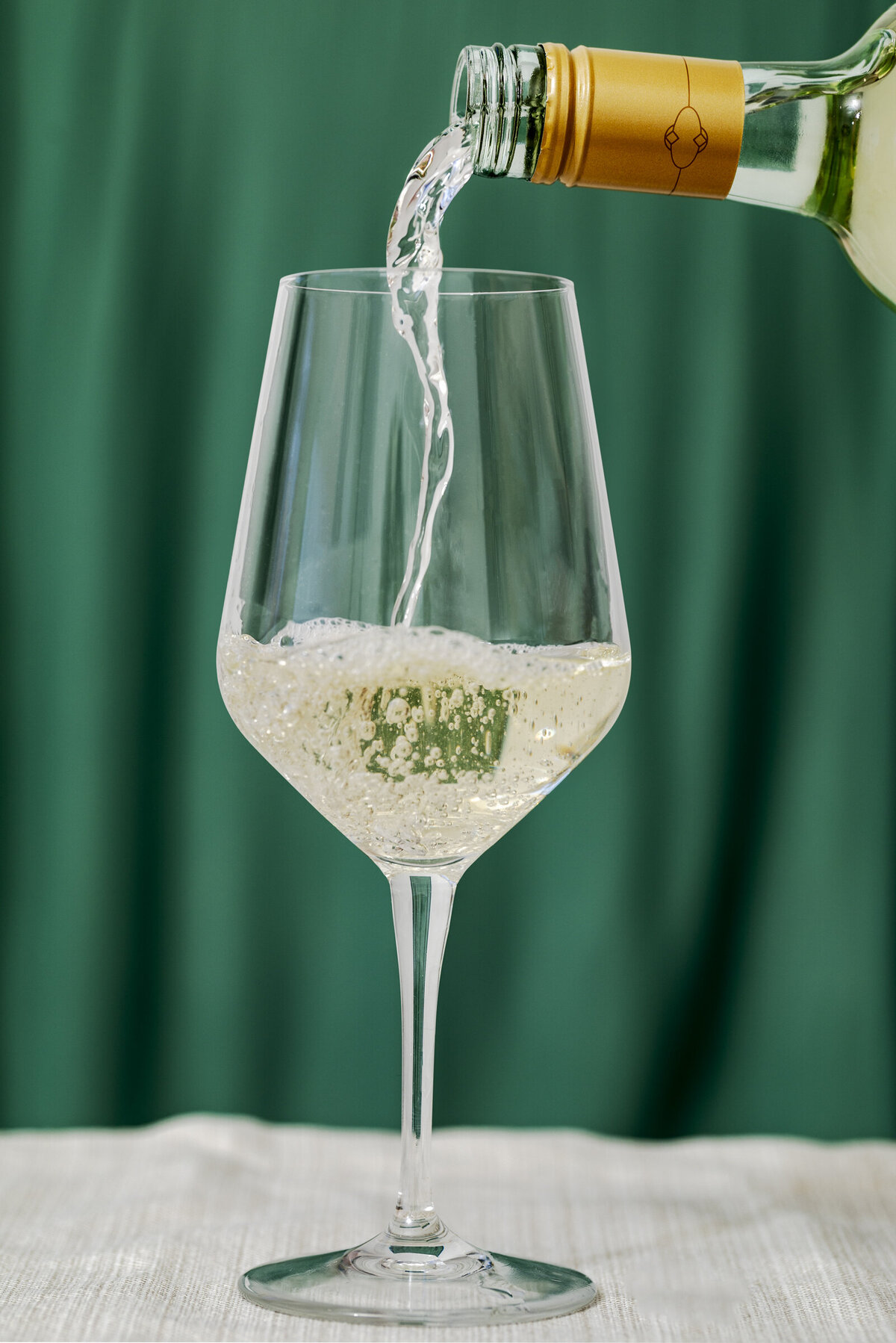 Menage a Trios Pino Grigio pour shot on a green velvet background for a holiday promotional.