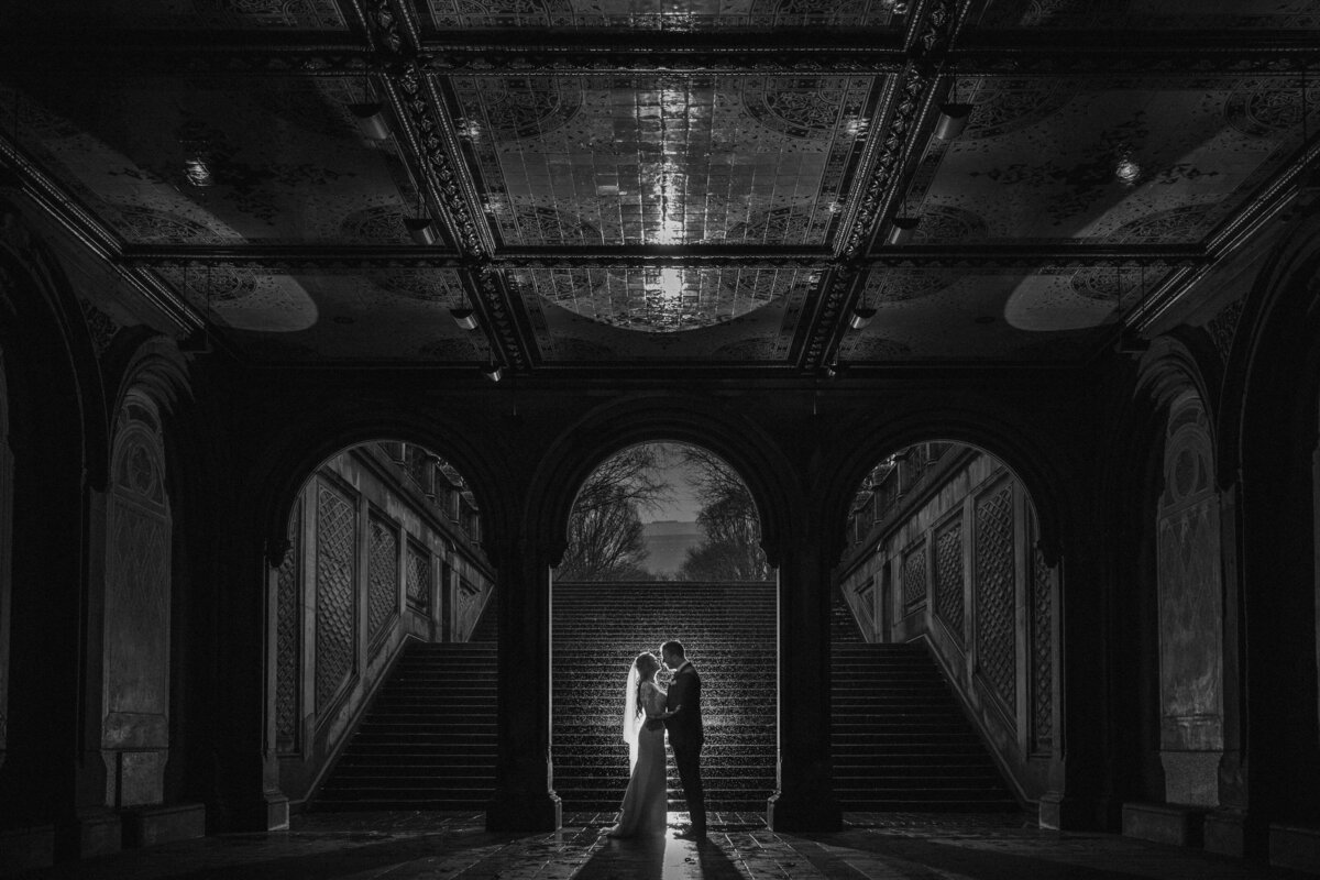 A bride and groom standing at the base of a large staircase together.