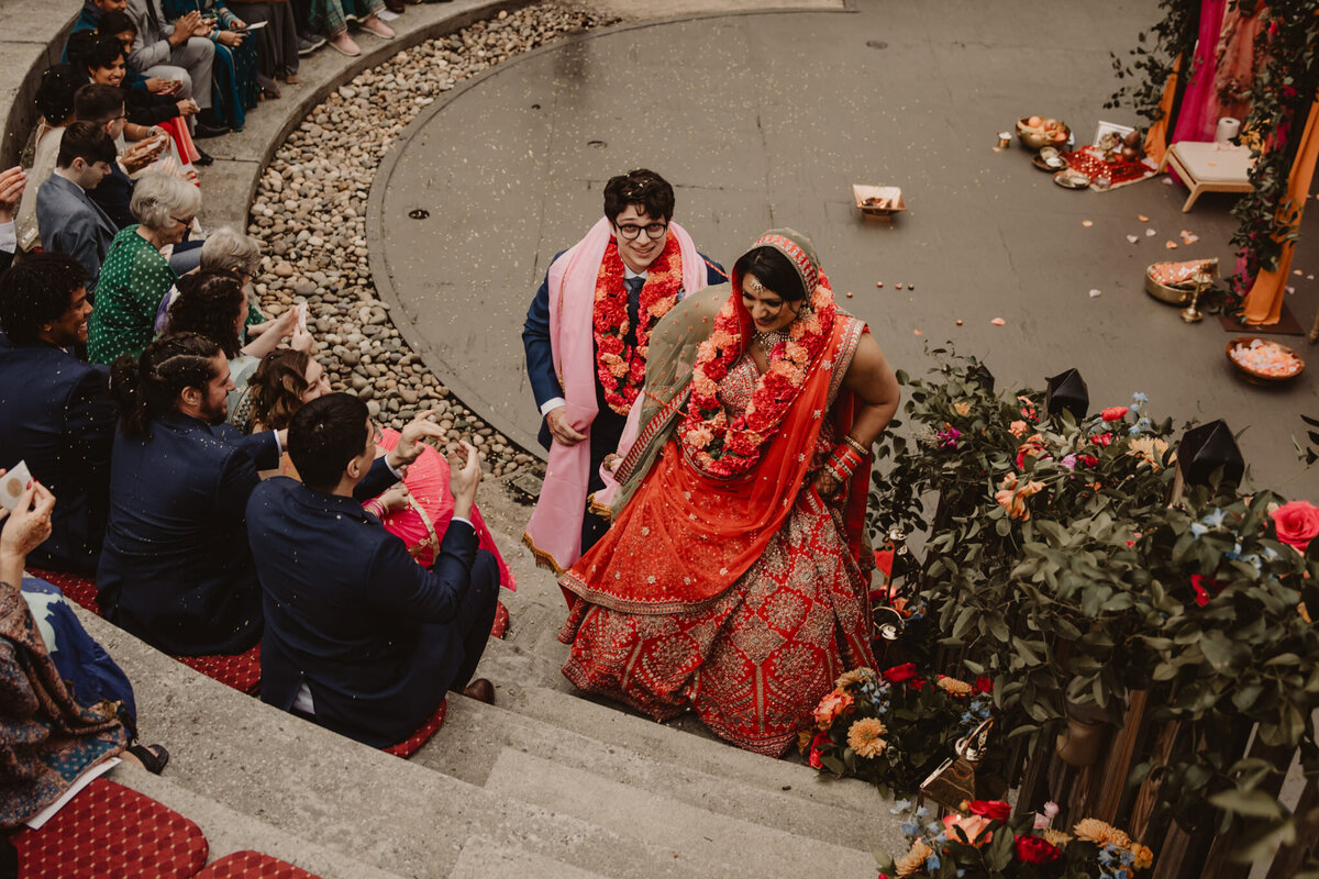 A newlywed couple walking up the stairs of an amphitheater 