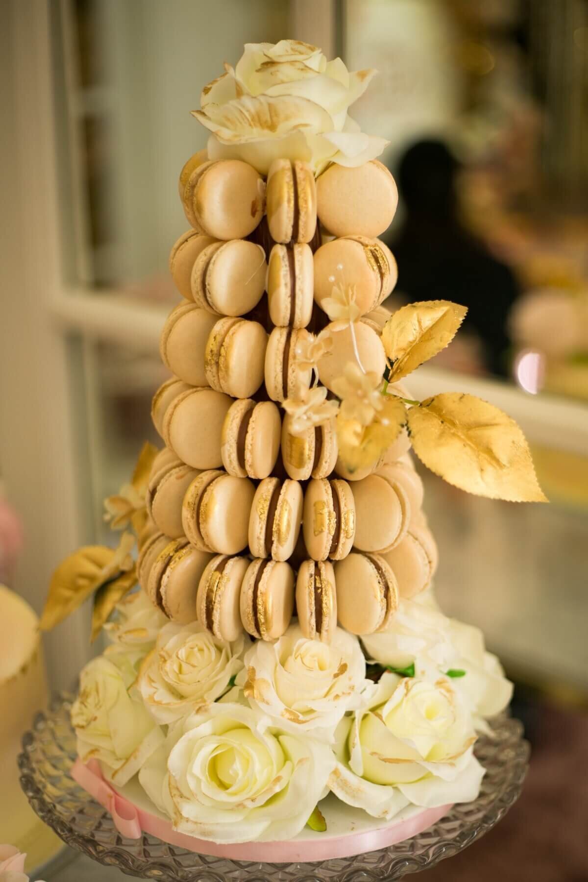 Decadent gold macaroon tower sat on a bed of white roses