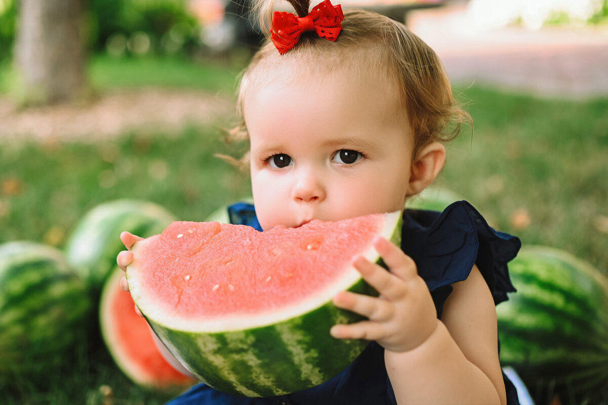 Close up photo of baby getting ready to take a bite of watermelon