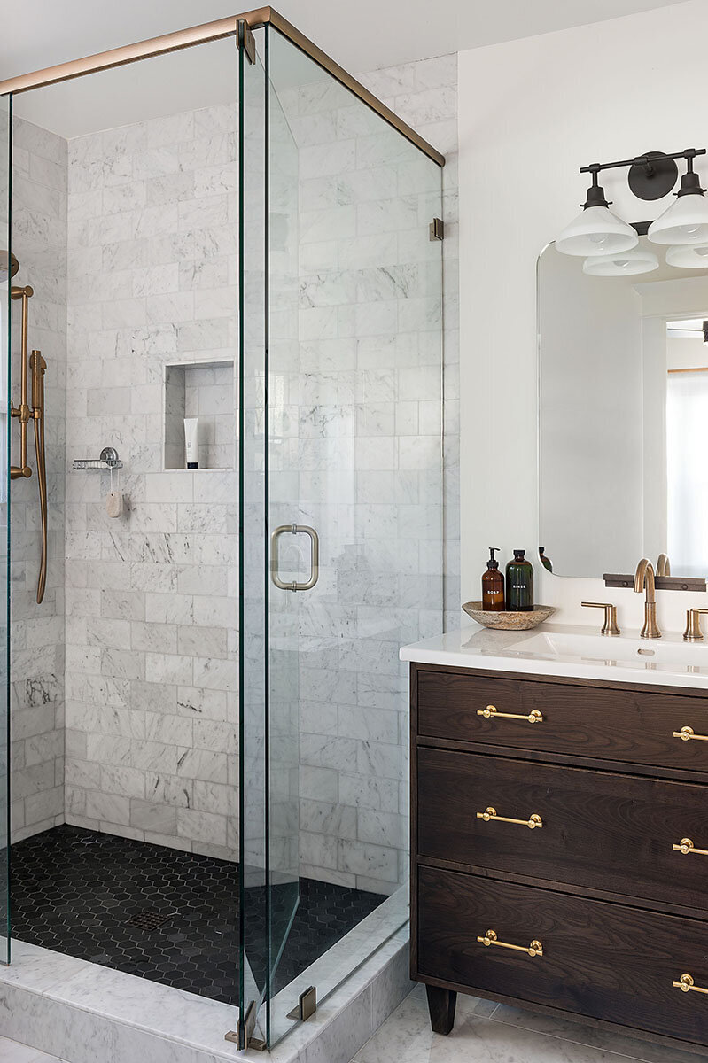 bathroom with marble shower and dark wood vanity