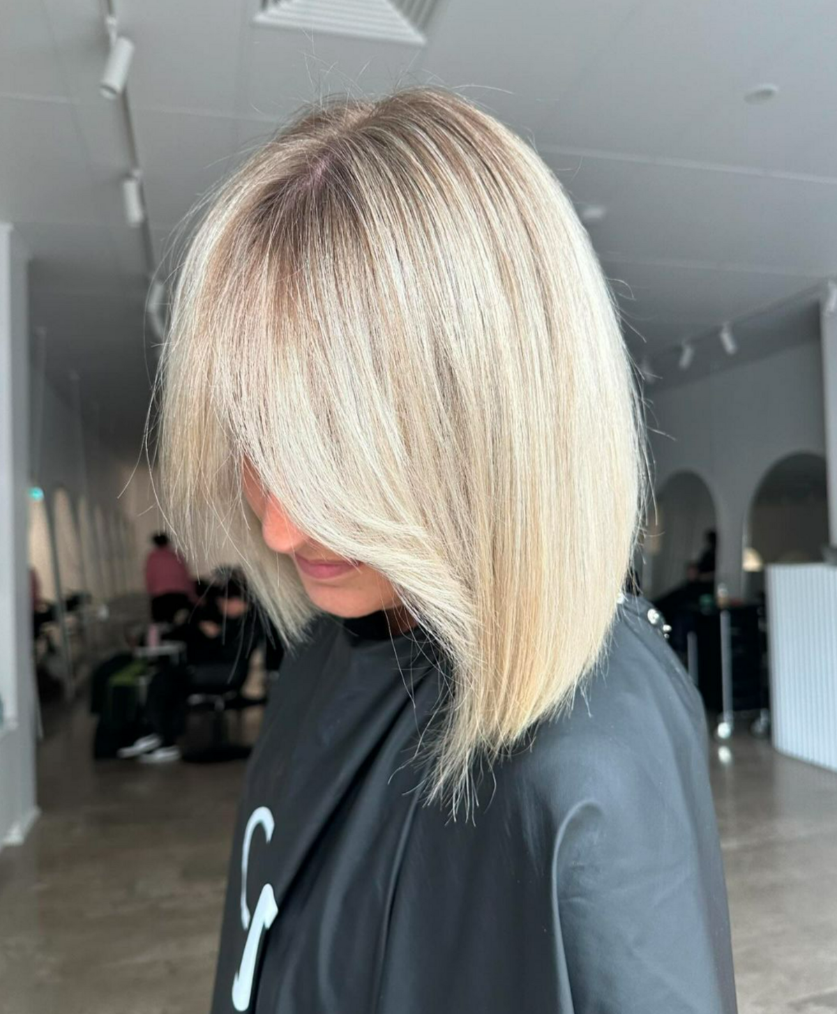 Girl wearing black hairdressers cape with short blonde hair cut