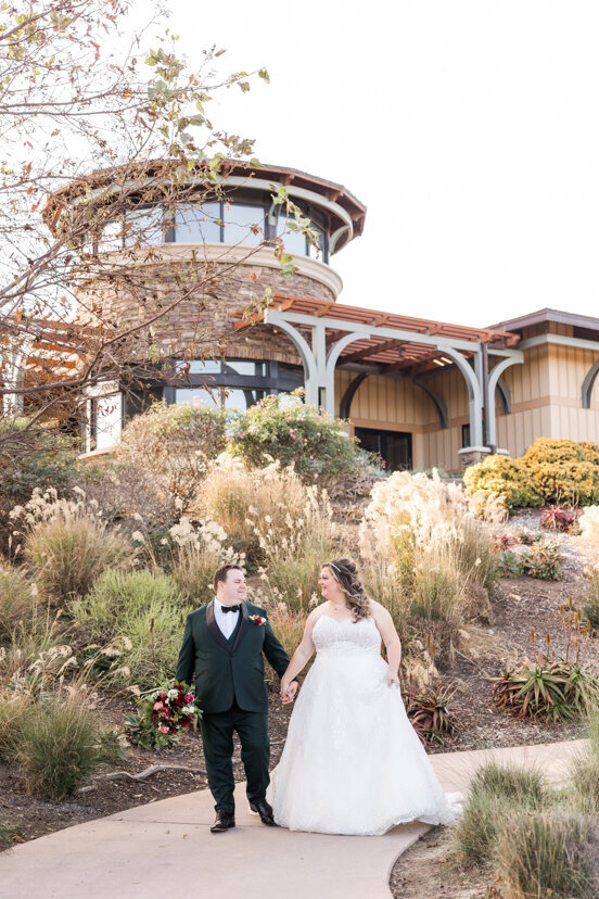 bride-and-groom-walking-by-clubhouse-the-crossings-carlsbad-wedding