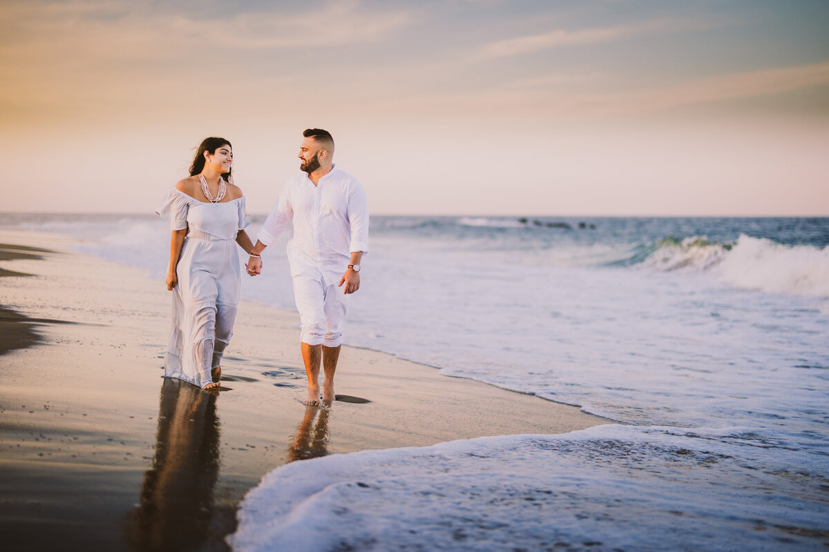 A couple walking along the shore during their engagement session at bradley beach in the jersey shore nj