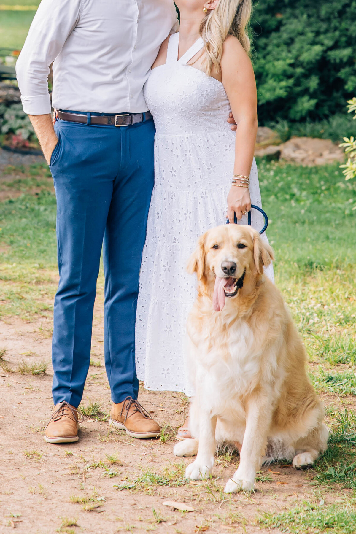 couple kissing in the background with golden retriever posing for family photos