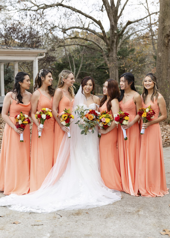 bridesmaids in coral dresses posing with bride