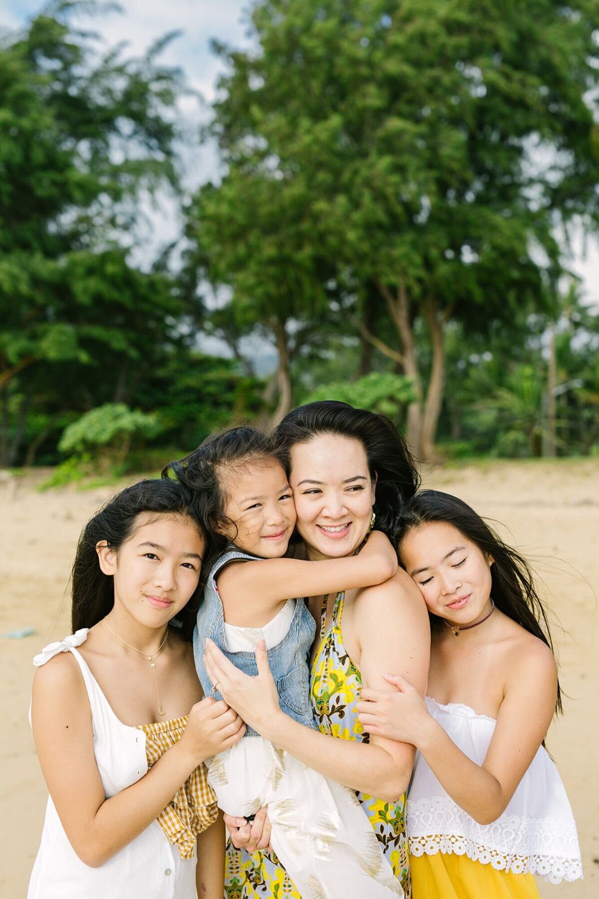A mother holds her three daughters tightly on the beach.