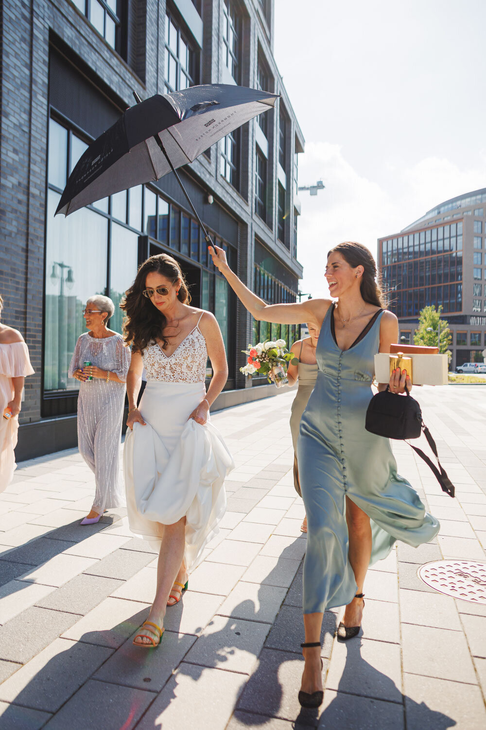 Maid of honor holding the umbrella for the bride