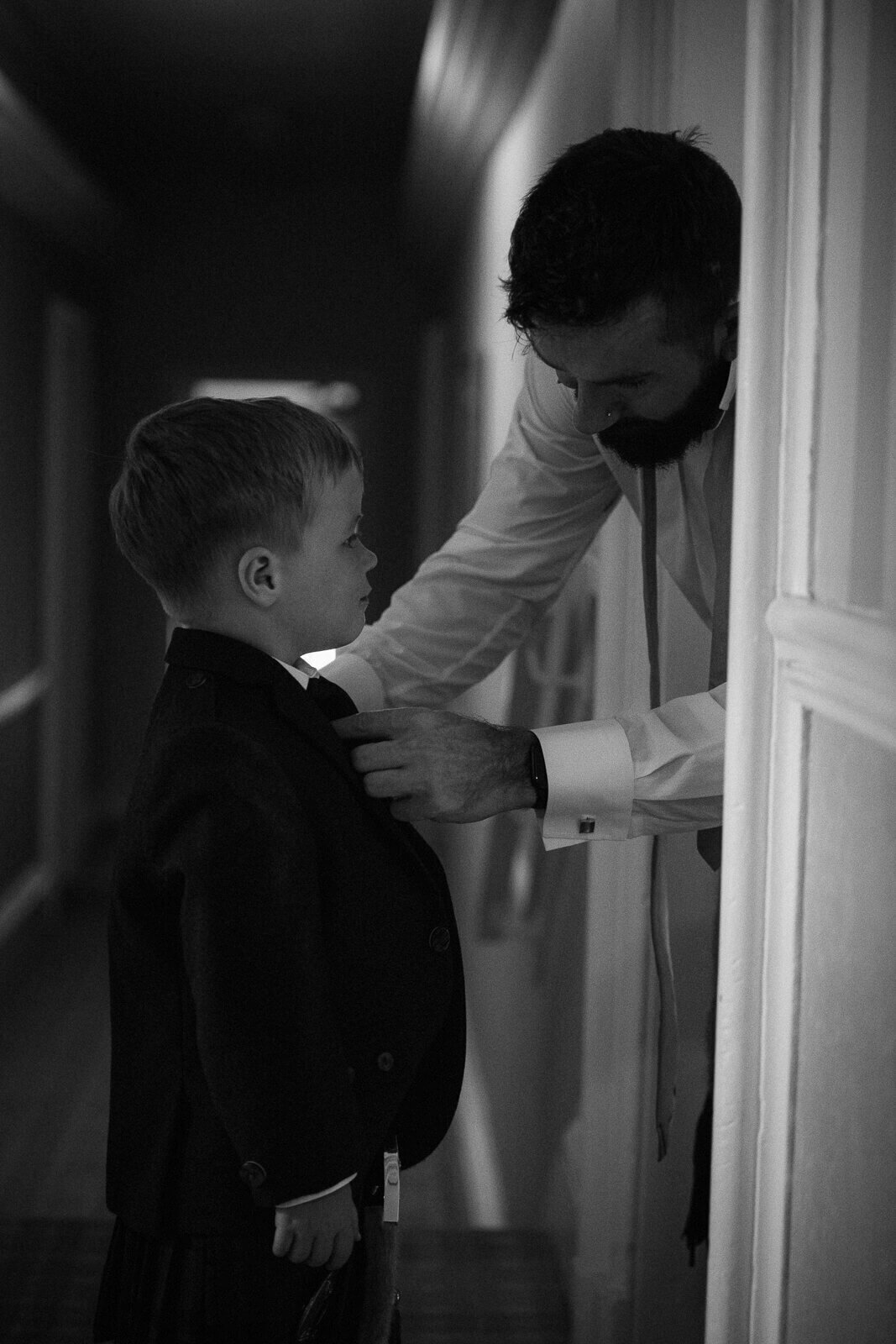 A young page boy has his bow tie adjusted by his uncle.