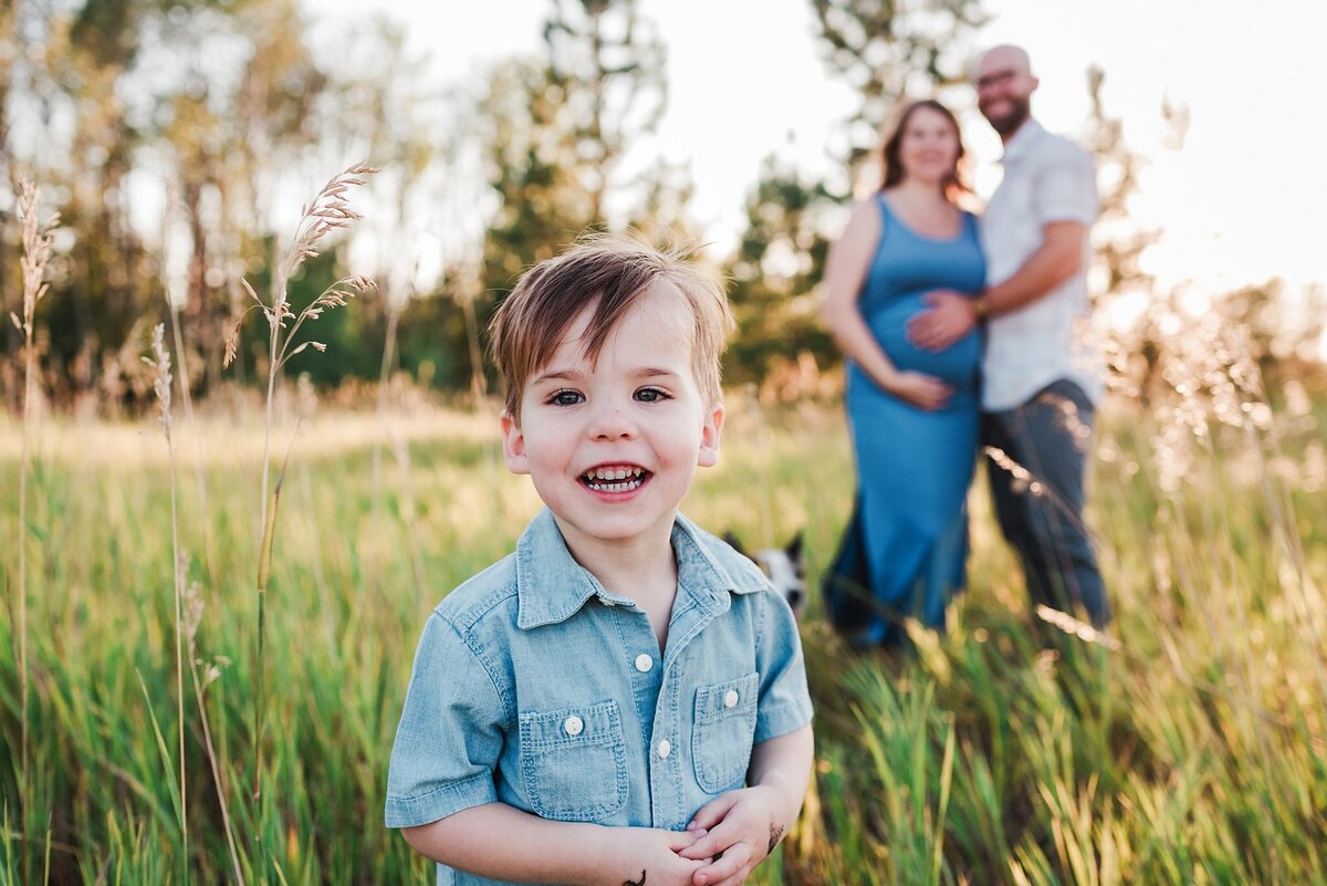 maternity pics with siblings in field, parents in background