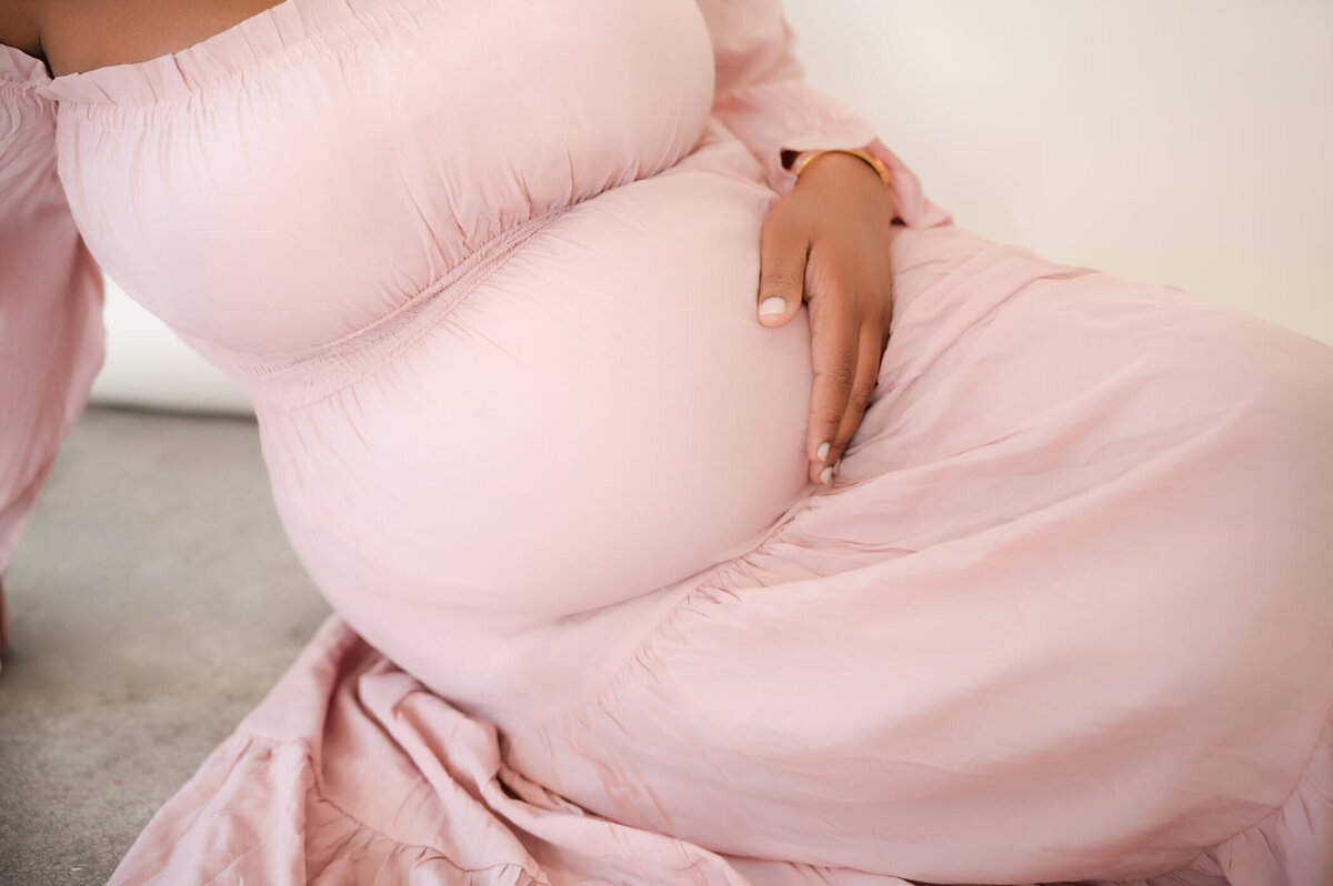 up close shot of baby bump in a pink dress