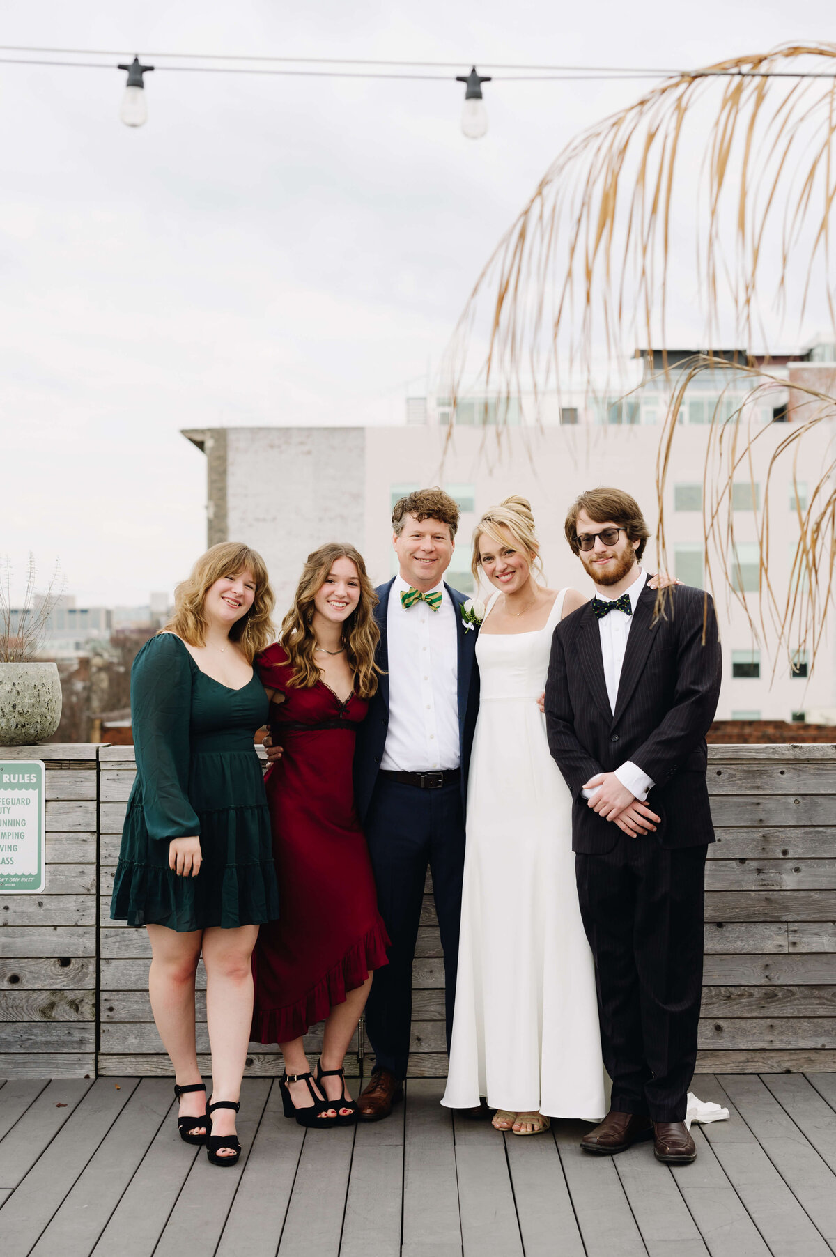 Richmond weddings photo with bride and groom posing with family  with the guests in emerald green and burgundy red