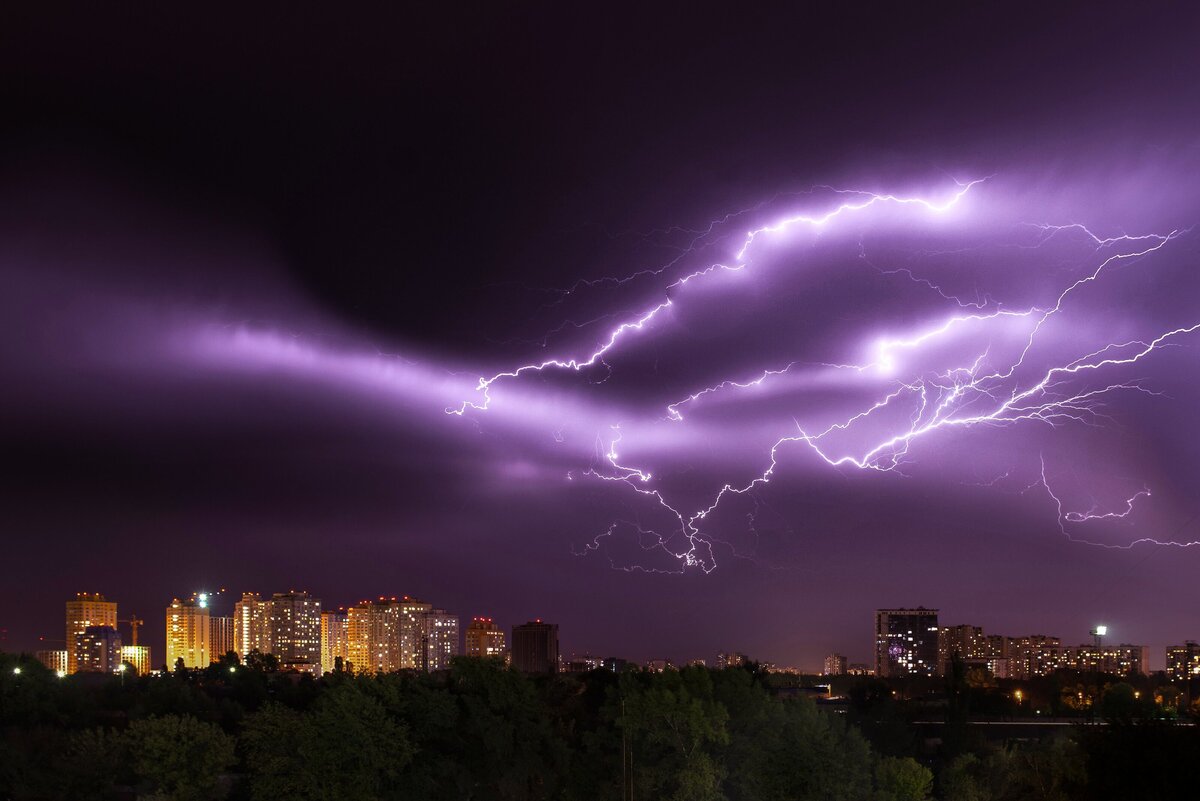 lightning shooting across the sky above a city
