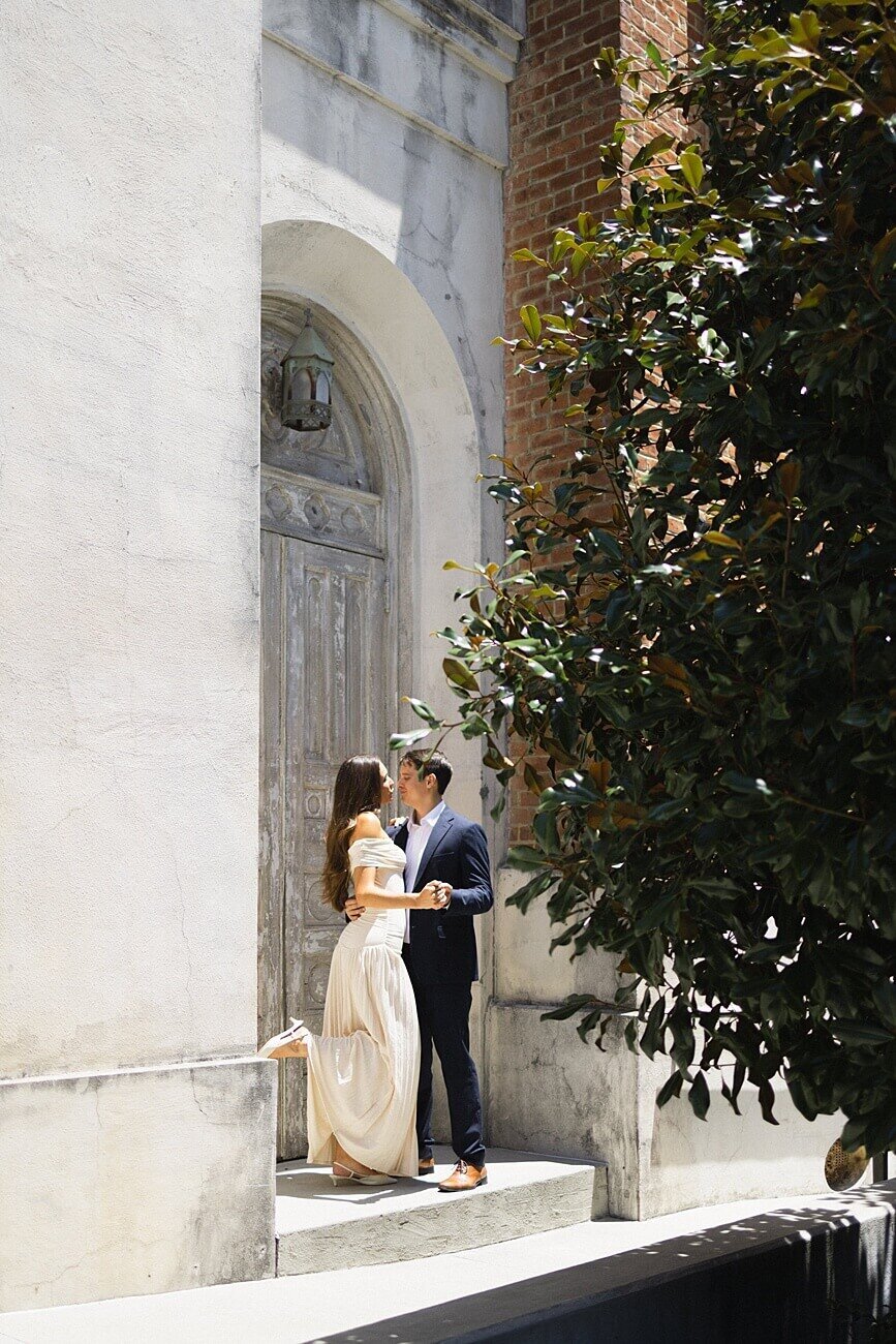 couple share a foot-popping kiss in front of Hotel Peter and Paul Chapel in New Orleans