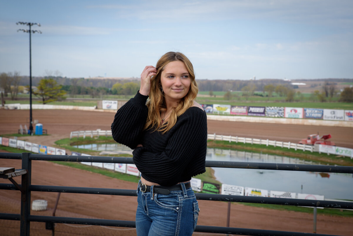 Denmark High School senior girl standing with hand in hair wearing black sweater and jeans.  141 Speedway